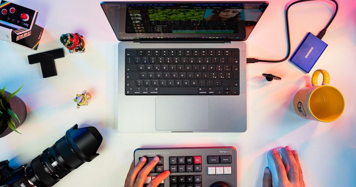 a person typing on a keyboard next to a laptop
